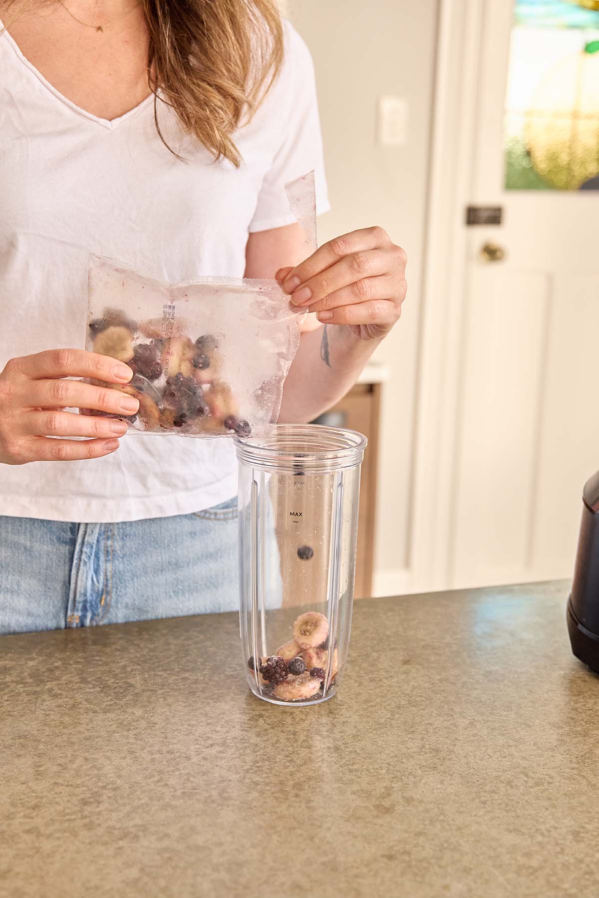 Woman pouring ready-to-blend smoothie pack into blender